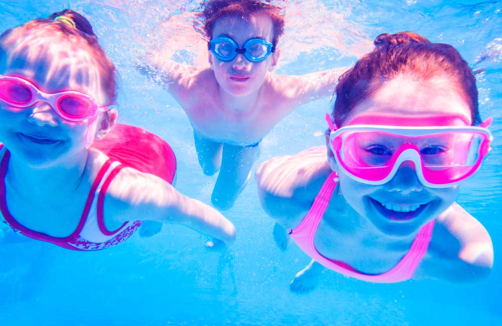 Niños nadando en piscina con gafas